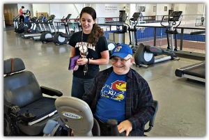 HAIL program volunteer and consumer Consumer on exercise bike with HAIL volunteer assisting
